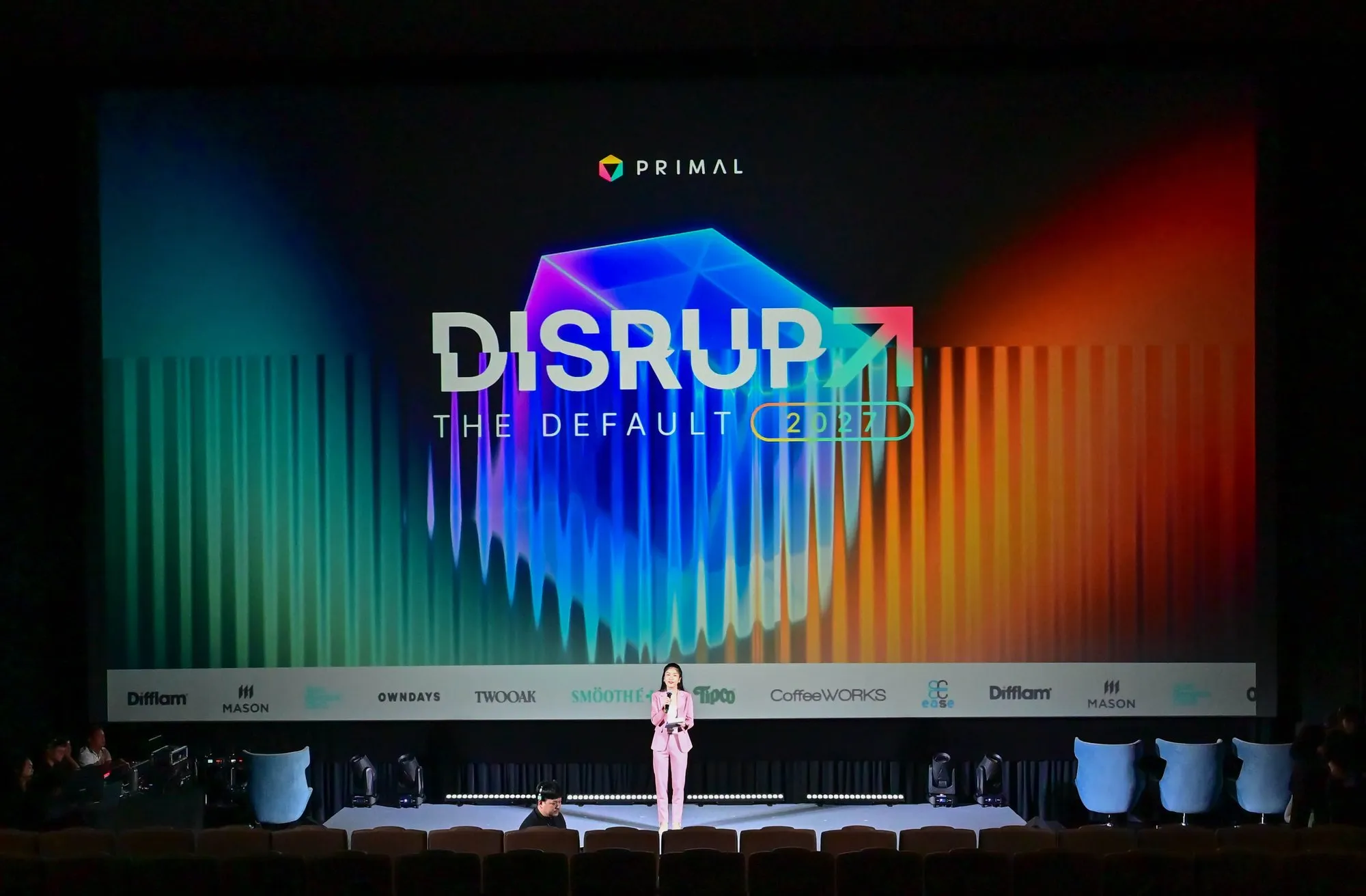 วิทยากรบนเวทีหน้าจอ Disrupt The Default 2027 ในงานของ Primal