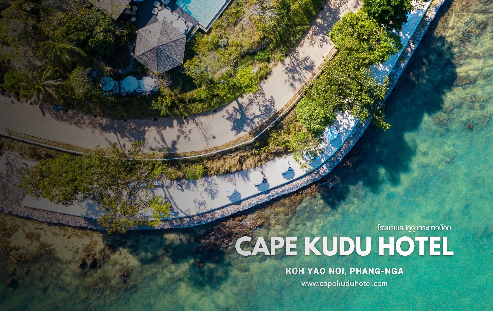 An aerial view of a curving path along a shore with white sun umbrellas, a pavilion and a pool terrace among trees, beside clear turquoise water, with the words Cape Kudu Hotel, Koh Yao Noi, Phang-nga and a web address at the lower right