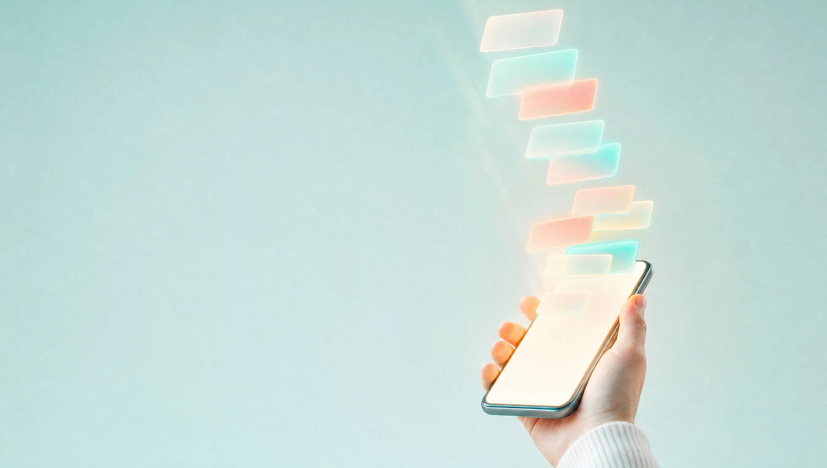 A hand holds a smartphone with a softly glowing blank screen on a pale aqua background, while a column of small frosted glass cards in teal, coral and yellow drifts up out of the screen.