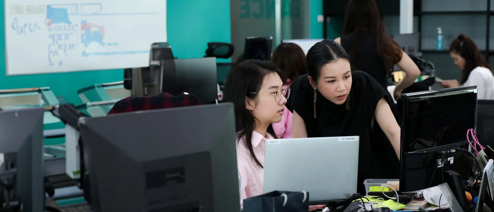 Primal colleagues at their desks reviewing work on a laptop
