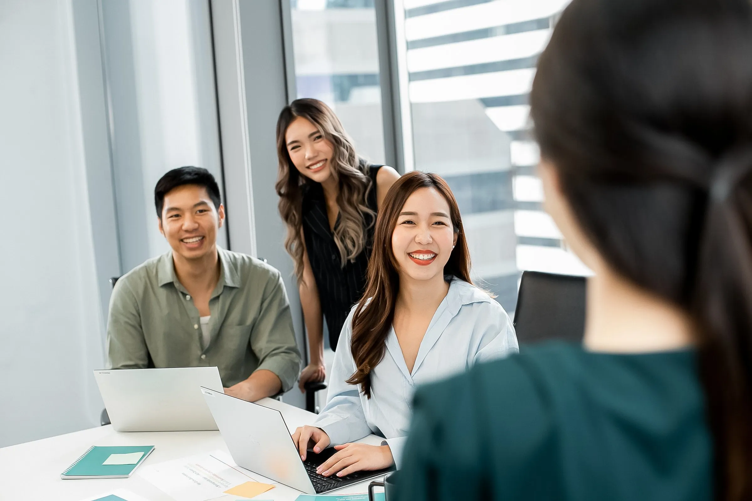 Primal colleagues smiling around a laptop in a meeting room