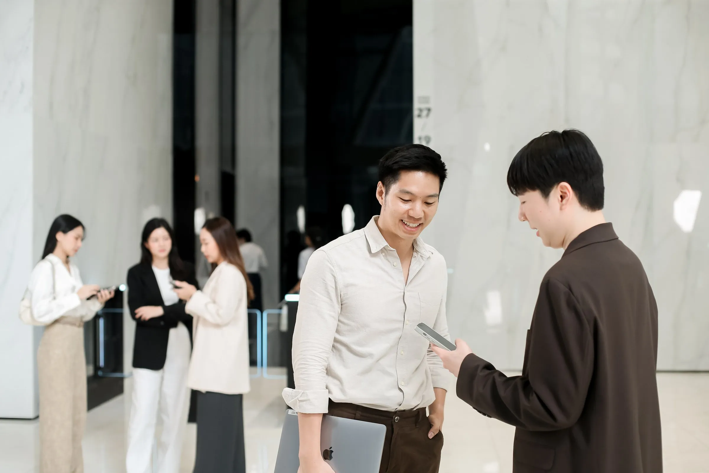 Primal colleagues talking in an office lobby, one holding a phone