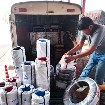 A man loading rolls of cable wrapped in white plastic into the back of a small truck