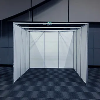 An empty exhibition booth with white panel walls and an aluminium frame on a grey checked carpet