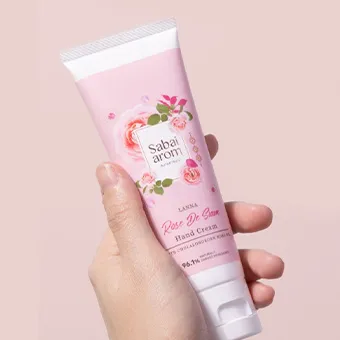 มือถือหลอดครีมทามือ Rose De Siam ของ Sabai arom สีชมพู บนพื้นหลังสีชมพูอ่อน