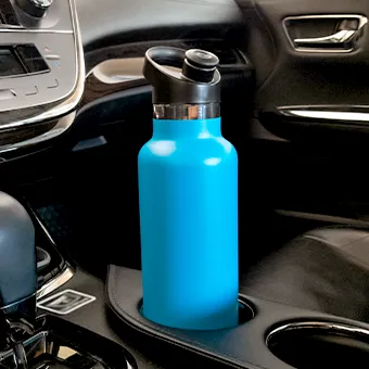 A blue insulated water bottle with a black lid standing in a car’s cup holder