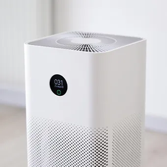A white air purifier with a round display reading 031, in a bright room