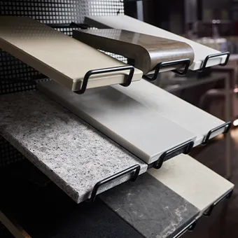 Stone-effect worktop samples in grey, cream and white on a black metal display rack
