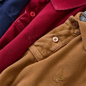 Polo shirts in navy, burgundy and tan laid in a row, the CC-OO bird logo embroidered on each