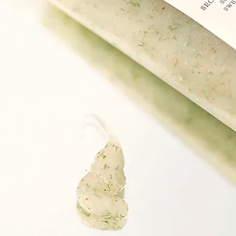 สครับเนื้อมีจุดสีเขียวและสีส้มบีบออกมาข้างหลอดบนพื้นสีขาว