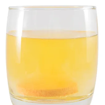 A glass of pale yellow water with a tablet dissolving at the bottom