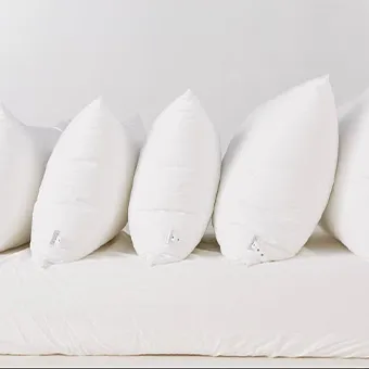 A row of white pillows standing on a white mattress