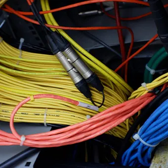 Bundles of yellow, orange and blue cables with 2 metal connectors hanging over them