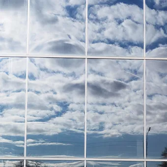 Clouds and blue sky reflected in the glass panels of a building