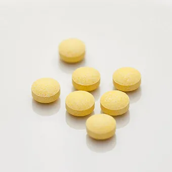 7 round yellow tablets on a white background