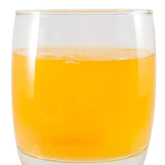 A glass of bright orange drink with small bubbles rising from the bottom
