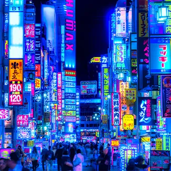 A crowded street at night under tall neon signs written in Japanese