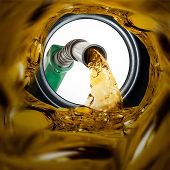 Golden fuel pouring from a pump nozzle, seen from inside the tank