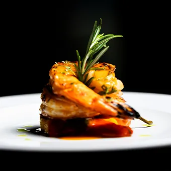 A grilled king prawn with a sprig of rosemary on a white plate against a black background