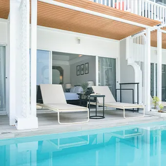 Two sun loungers on a terrace outside a hotel room, with a pool in front