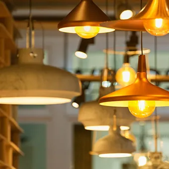 Copper and grey pendant lamps with glowing bulbs hanging from a ceiling