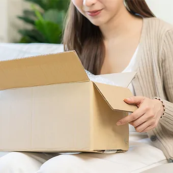 A woman opening a cardboard delivery box on a sofa