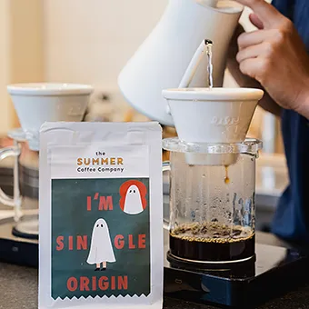 A bag of I’m Single Origin coffee in front of a pour-over brew