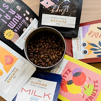 A tin of roasted coffee beans among The Summer Coffee bags