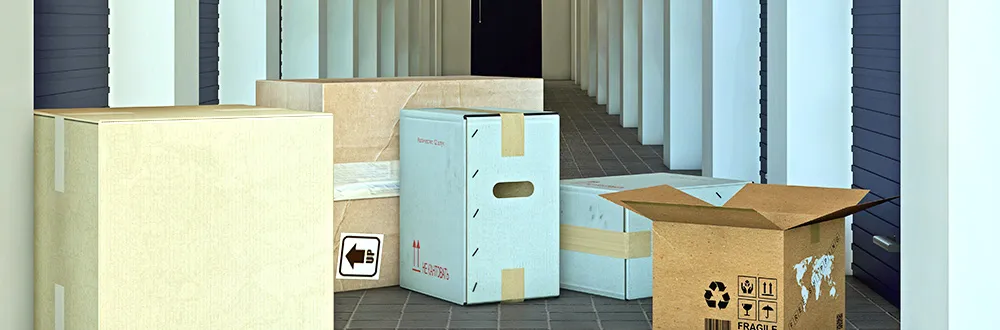 Cardboard boxes of different sizes on a tiled floor in a corridor of blue storage units