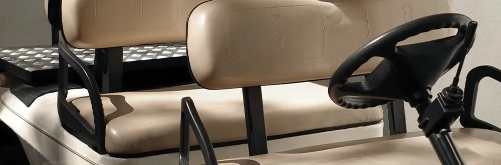 A close view of the beige seats and black steering wheel of a golf cart