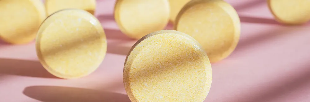 Round yellow tablets standing on their edges on a pink background in bright sunlight
