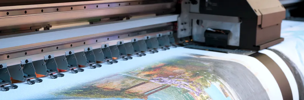 A wide-format printer printing a colourful painted scene onto a wide roll of material