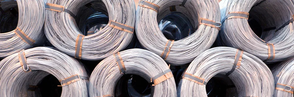 Coils of steel wire stacked in rows, each coil held by metal straps