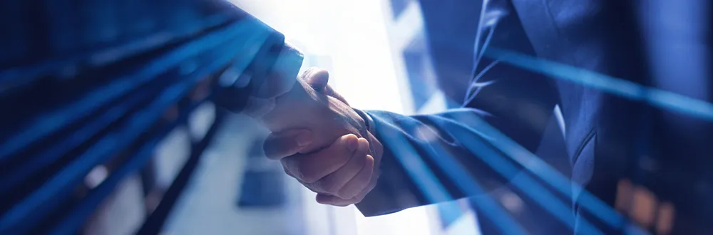 Two people in dark suits shaking hands, with streaks of blue light across the picture