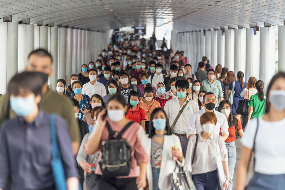 Hundreds of people walking while wearing face masks